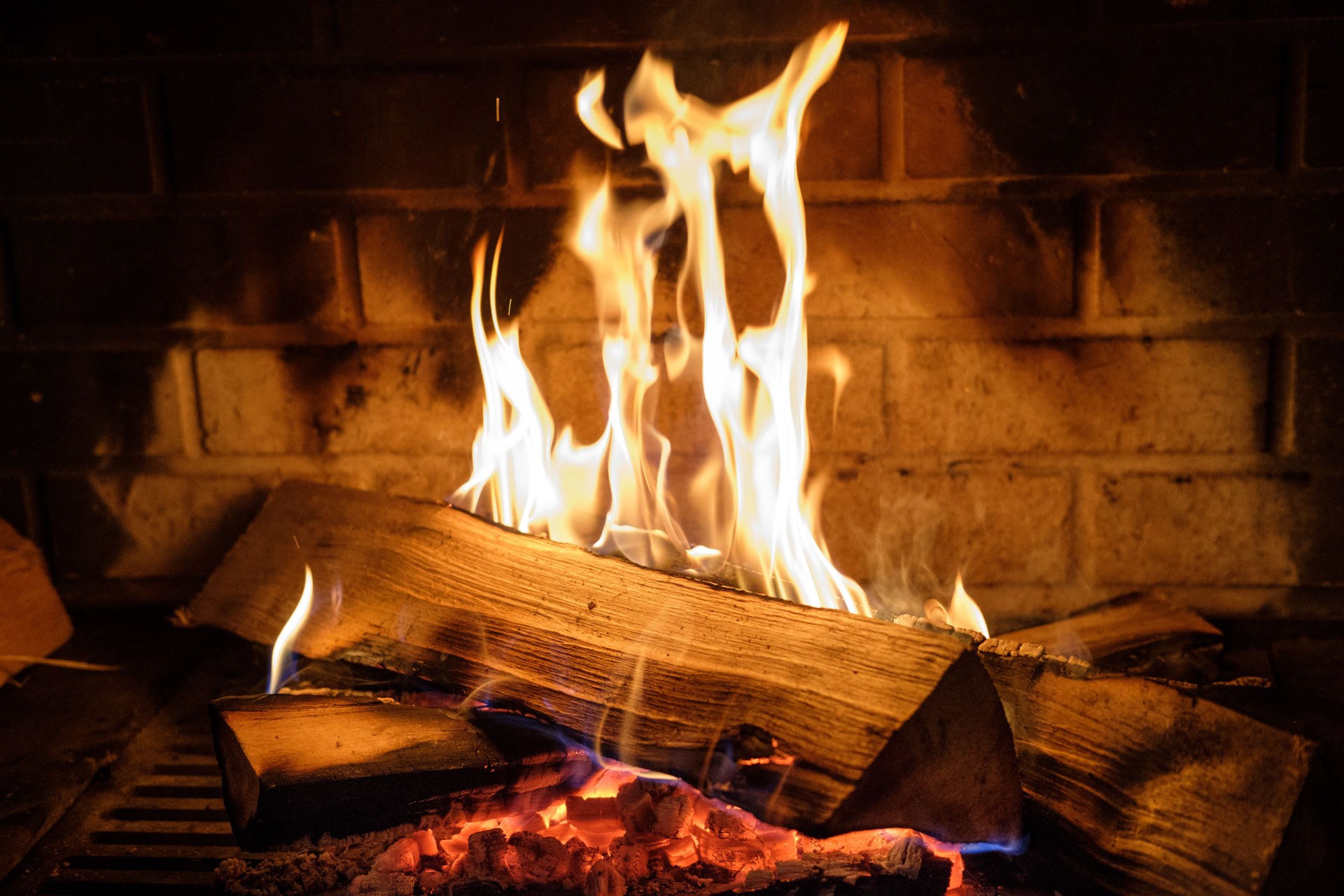 Brænde brænder i pejs med flammer og gløder.